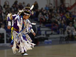 A male Indigenous dancer performs at a ceremony in War Memorial Gymnasium.