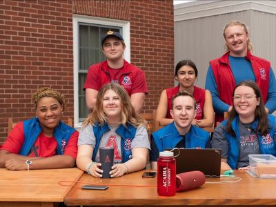 A group of RA's, including Angel Percentie, smile at their registration table during move-in at the Residence Quad