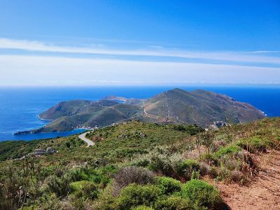 A view of the Mani Peninsula, a hilly Greek landscape covered with vegetation and crossed by winding roads.