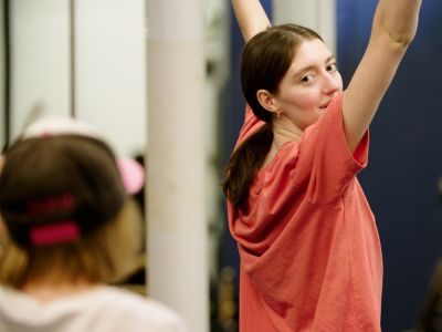 Anna Lukeman smiles and looks over her shoulder while she demonstrates dance choreography to children.