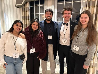 A smiling group of young alumni pose inside Ashburn Golf Club.