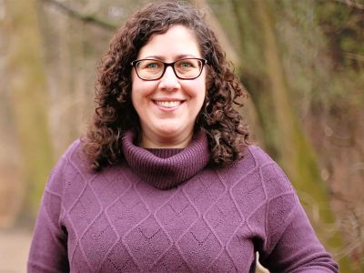 Dr. Rebecca Casey smiles at the camera in a park setting.
