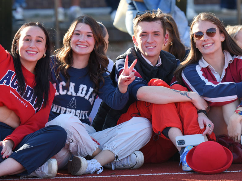 A group of friends in Acadia apparel smile as they pose for a group photo