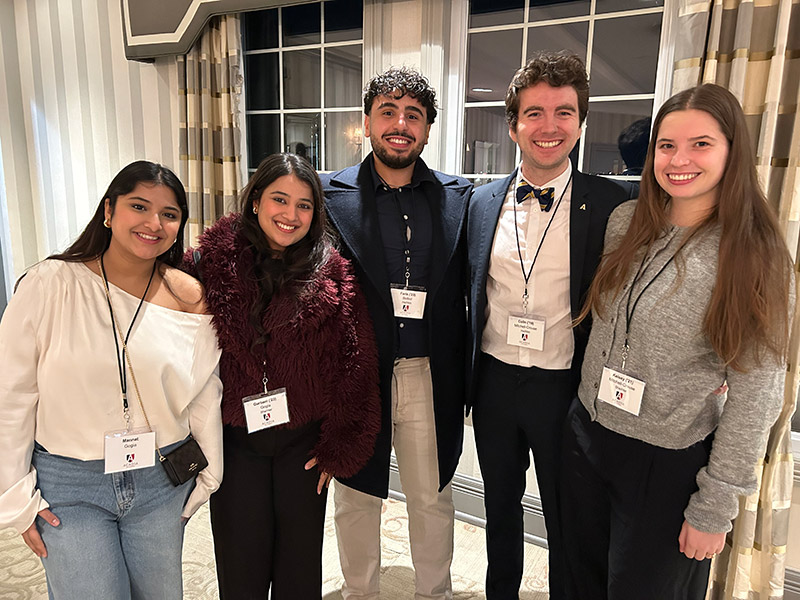 A smiling group of young alumni pose inside Ashburn Golf Club.