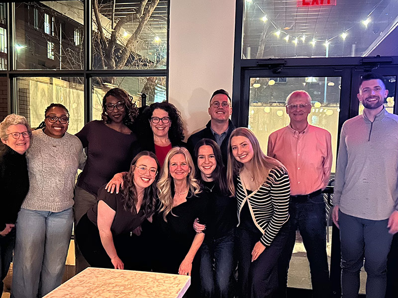 Acadia staff and alumni smile for a group photo in an event space