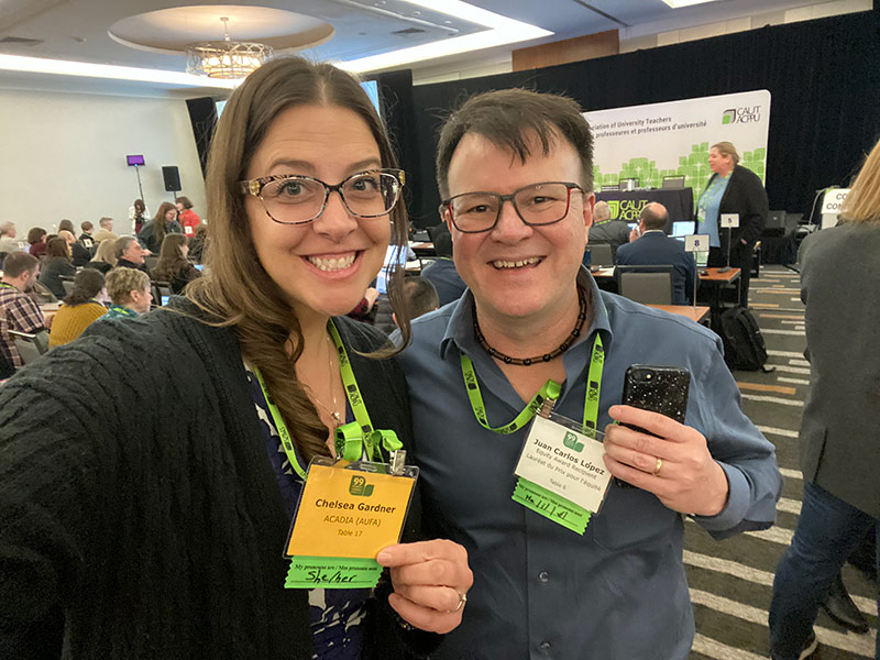 Drs. Chelsea Gardner and Juan Carlos López smile and hold up their identity badges at the CAUT conference