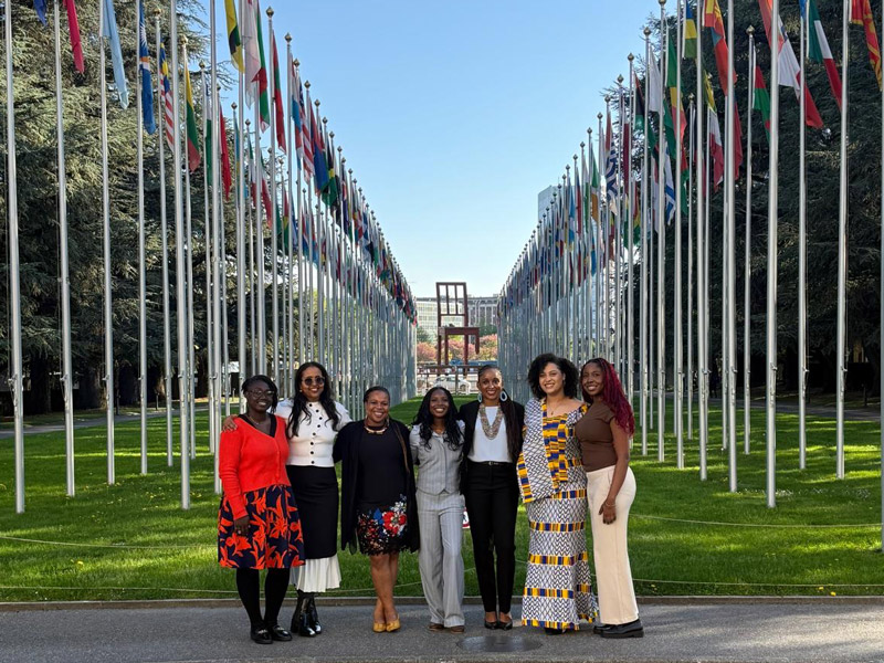The Acadia delegation poses outside the United Nations Office in front of the array of flags and the Broken Chair monument.