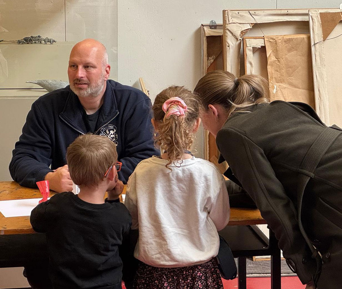 Children and visitors look at artifacts on a table