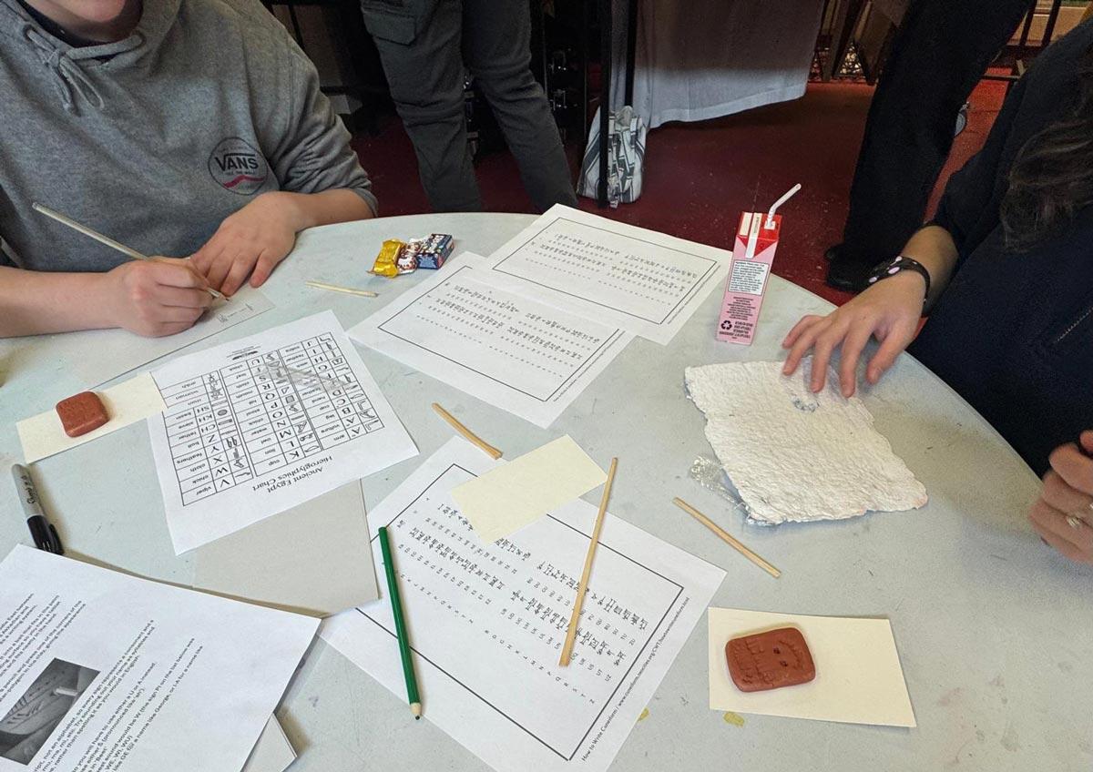 Students conduct an exercise with cuneiform tablets and sheets of character translations.
