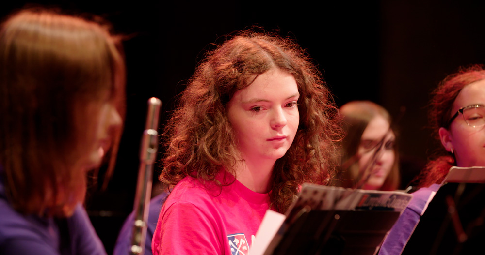 Woodwind players look to their sheet music during a concert band rehearsal.