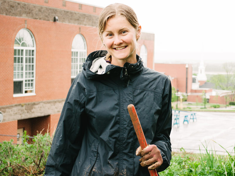 Dr. Liesel Carlsson stands in the Acadia Community Farm herb garden above Wheelock Dining Hall on a foggy spring day.