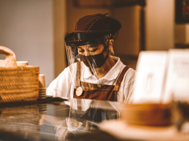 A retail worker wearing a face shield and mask during the COVID-19 pandemic. Image courtesy of Dapiki Moto on Unsplash.