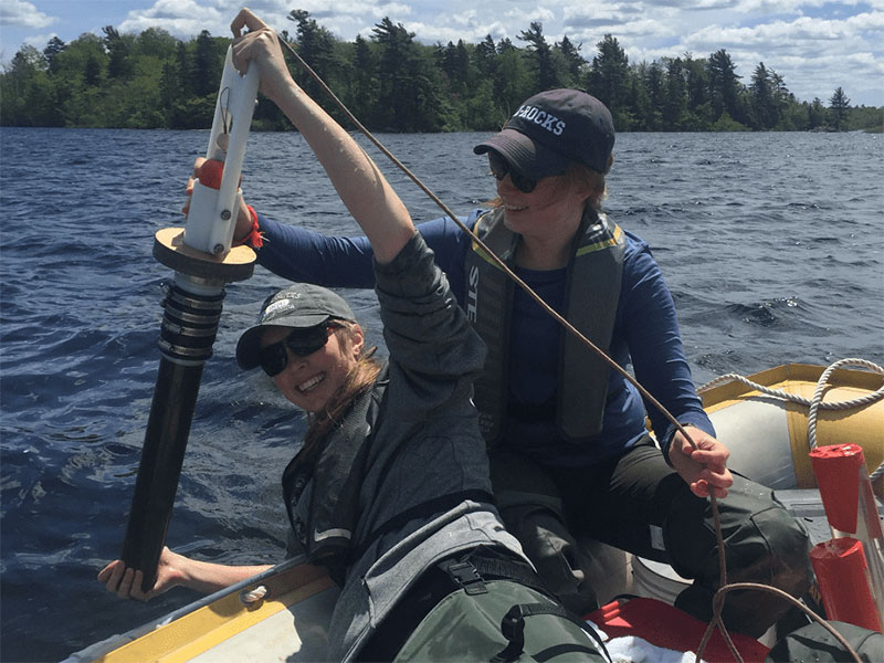 Julia Crews (left), BSc Honors ENVS ‘20, collecting a lake sediment core with a gravity corer on Gaspereau Lake, assisted by Lauren Muzak Ruff (right), MSc ENVS ‘21. Photo taken before COVID-19.