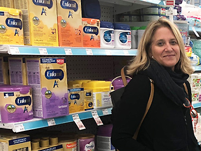 Professor Lesley Frank stands next to a shelf of infant formula in a supermarket. Photo courtesy of Mary-Catherine McIntosh/CBC.