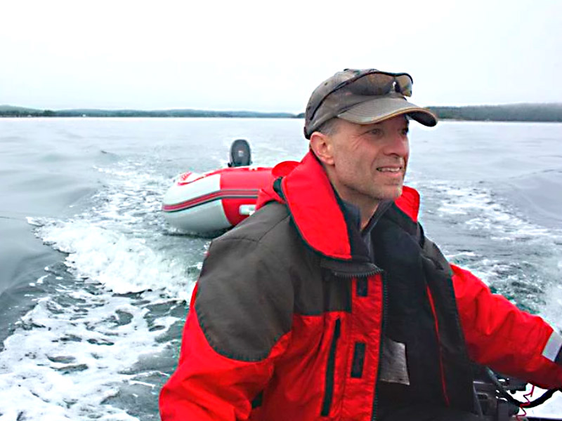 Dr. Mark Mallory smiles while piloting a boat