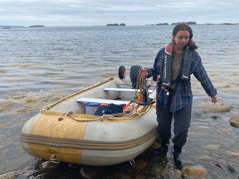 Student researcher Natalie Koopman pulls an inflatable boat to shore.